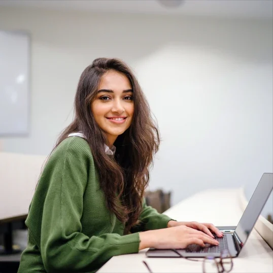 Smiling woman working on a laptop.