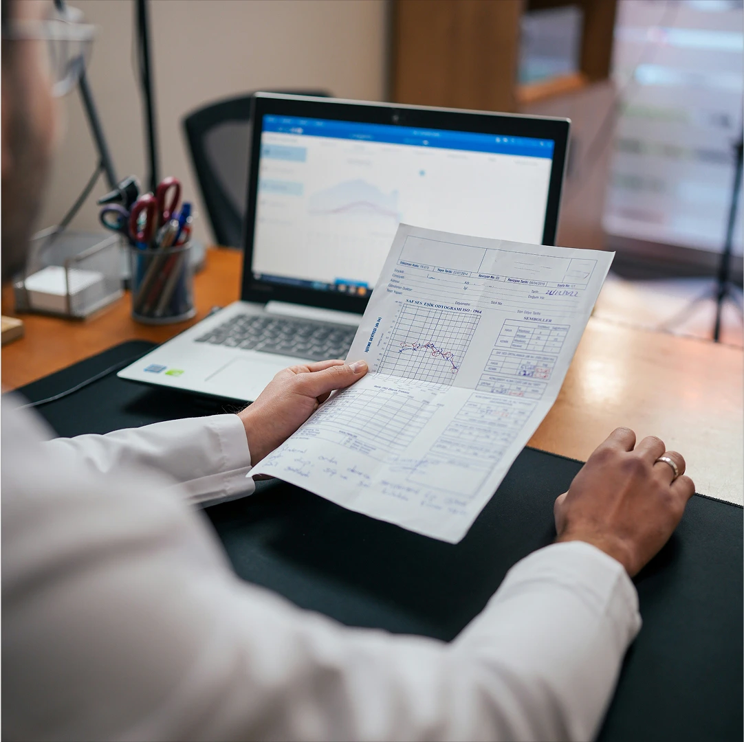 Healthcare provider analyzing patient data, combining traditional paper records with digital healthtech solutions displayed on a laptop
