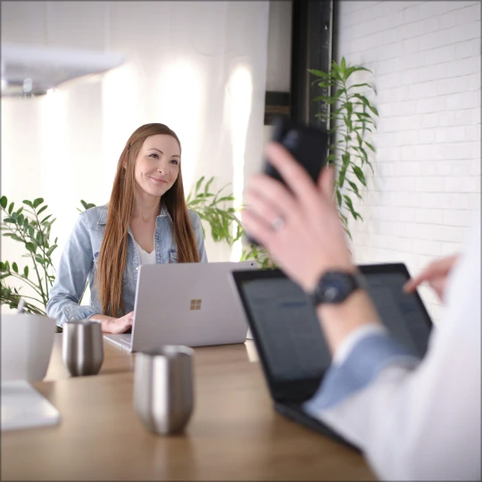 Man and woman working on laptops in a modern office, processing mortgage applications.