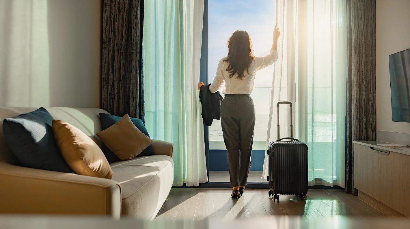 Woman looks out at the bright ocean from her hotel room