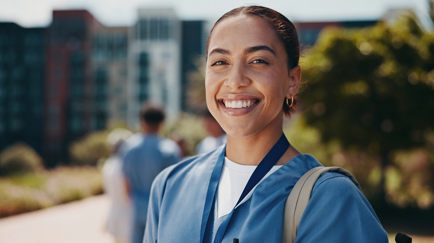 A smiling woman in a blue medical coat with short dark hair