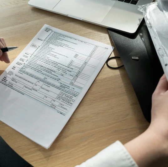 Man filling out medical bills on table with laptop and documents