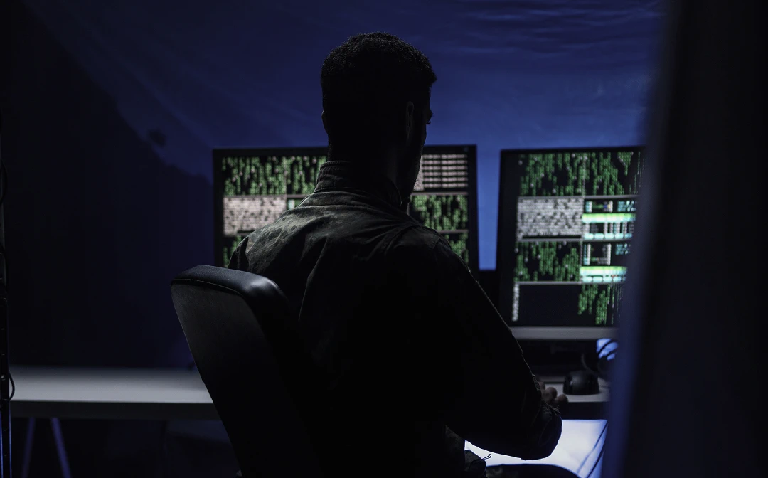 A man is sitting in front of multiple monitors, monitoring the accuracy of data and ensuring it is updated on time.