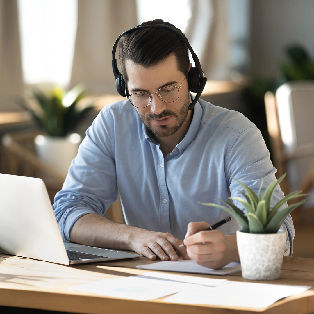 A focused man wearing a headset and a blue shirt is providing high-quality customer support
