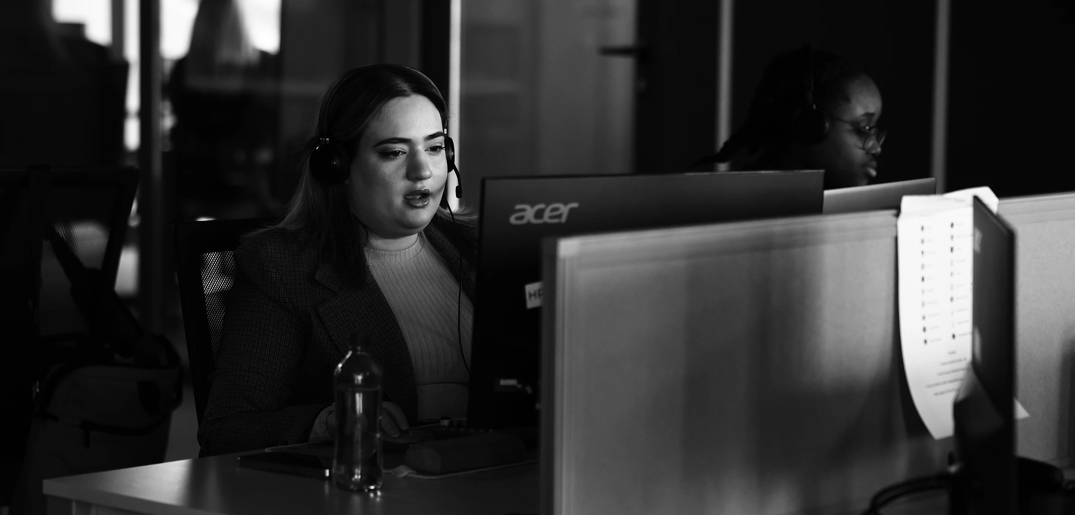 Female customer support agent wearing a headset, looking at a computer screen