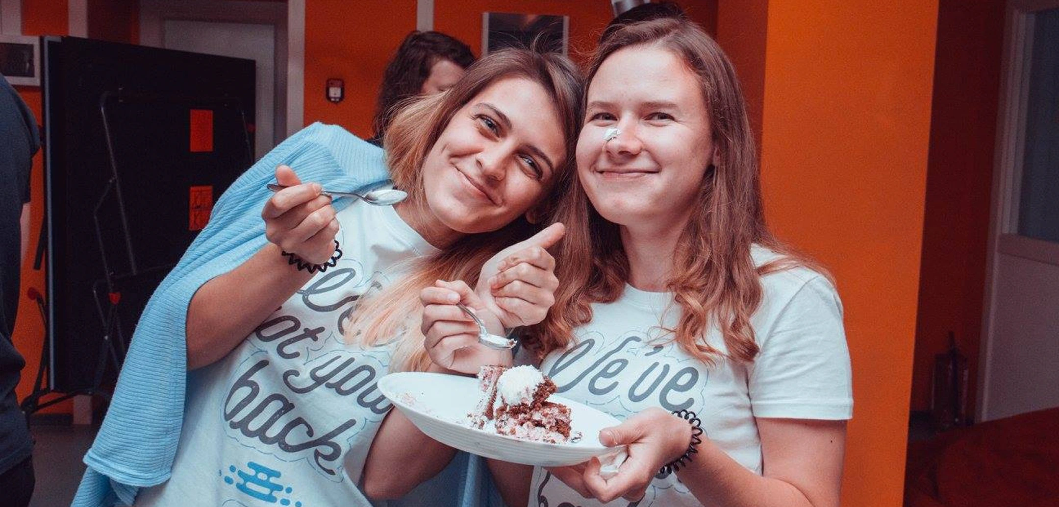 Smiling women enjoying cake at a celebratory event.