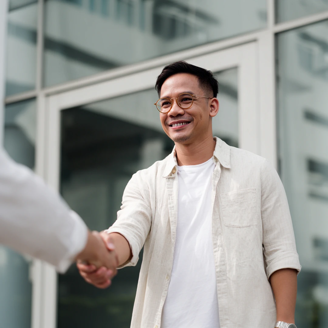 Two people shaking hands in front of a modern building