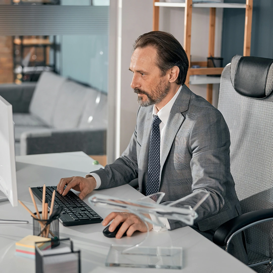 Man in a suit using a desktop computer in an office