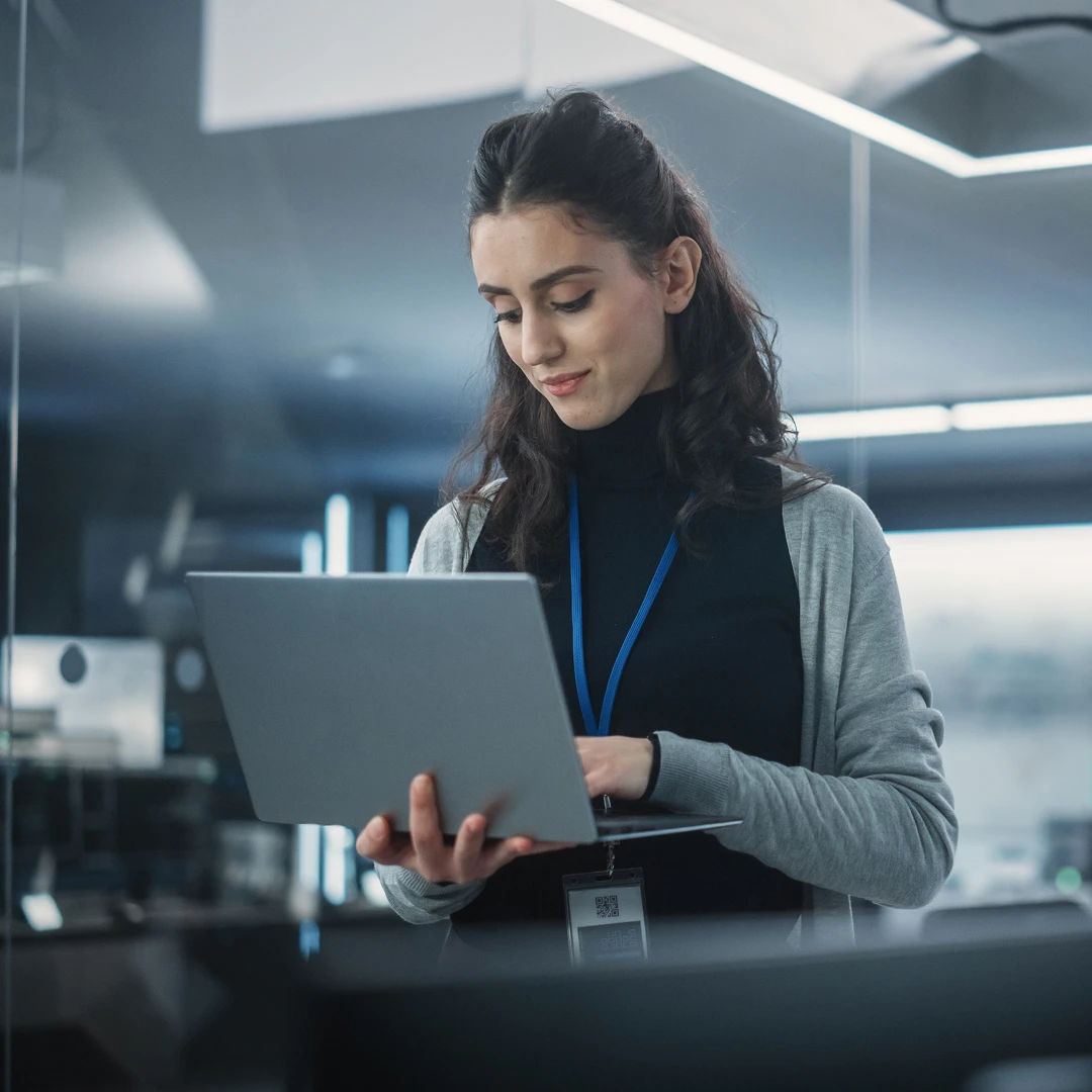 Woman holding and using a laptop in a modern office