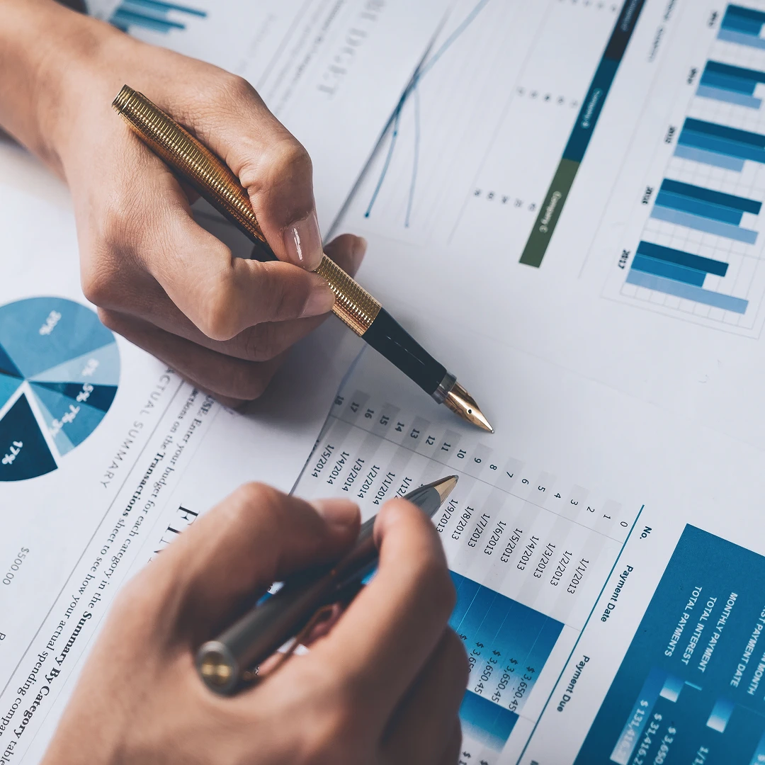 Close-up of two men's hands holding pens and analyzing documents