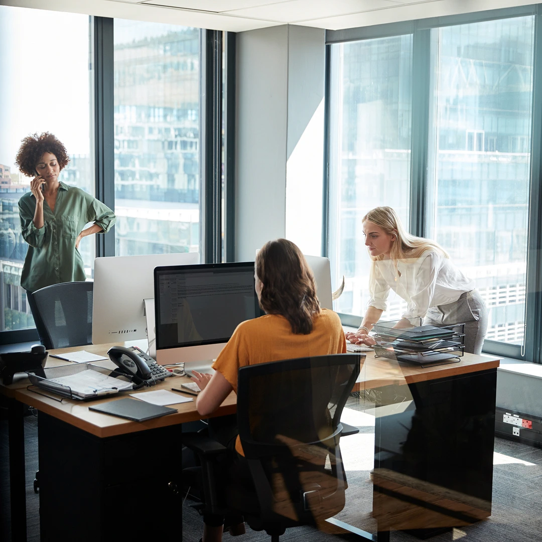 Three women working in a modern office with large windows