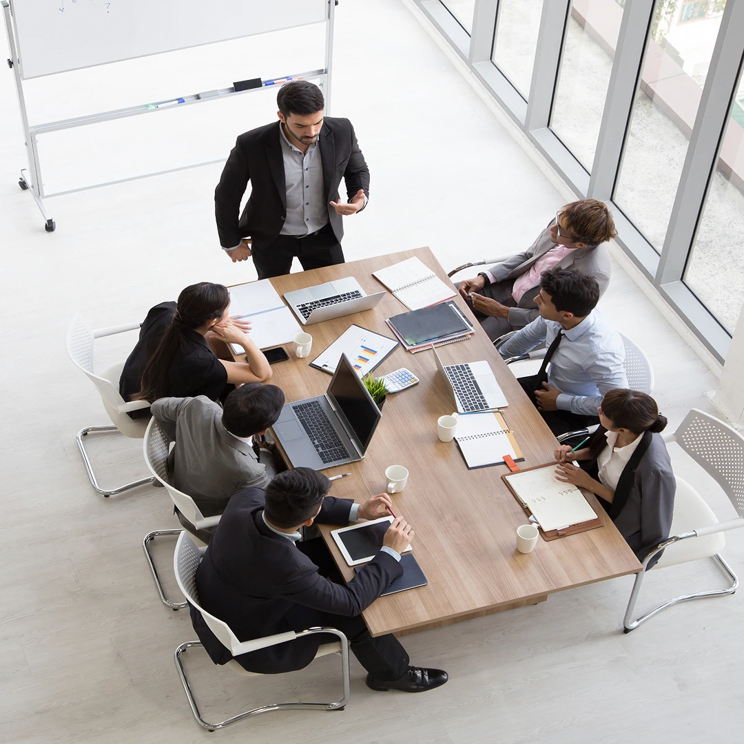 Overhead view of business team during a meeting around a conference table with laptops and notes