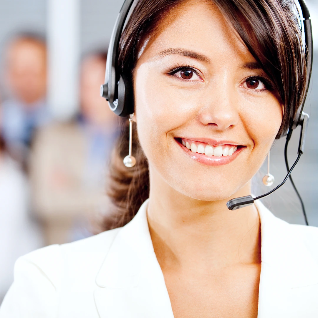 Smiling female customer support agent with dark hair wearing a white blazer and headset