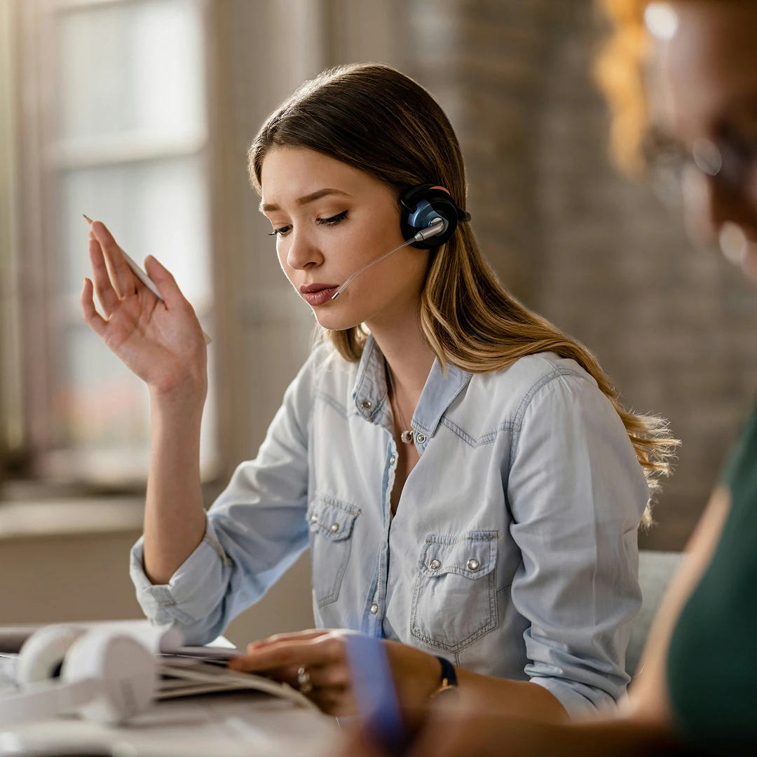 Retail customer service agent wearing a headset, taking notes during a call