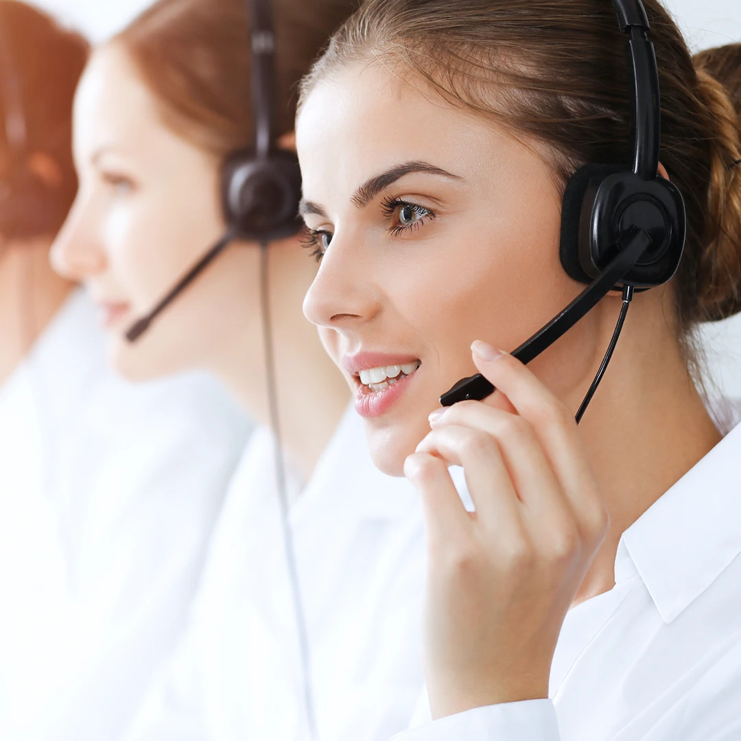 Friendly group of female customer support agents wearing headsets and white blouses
