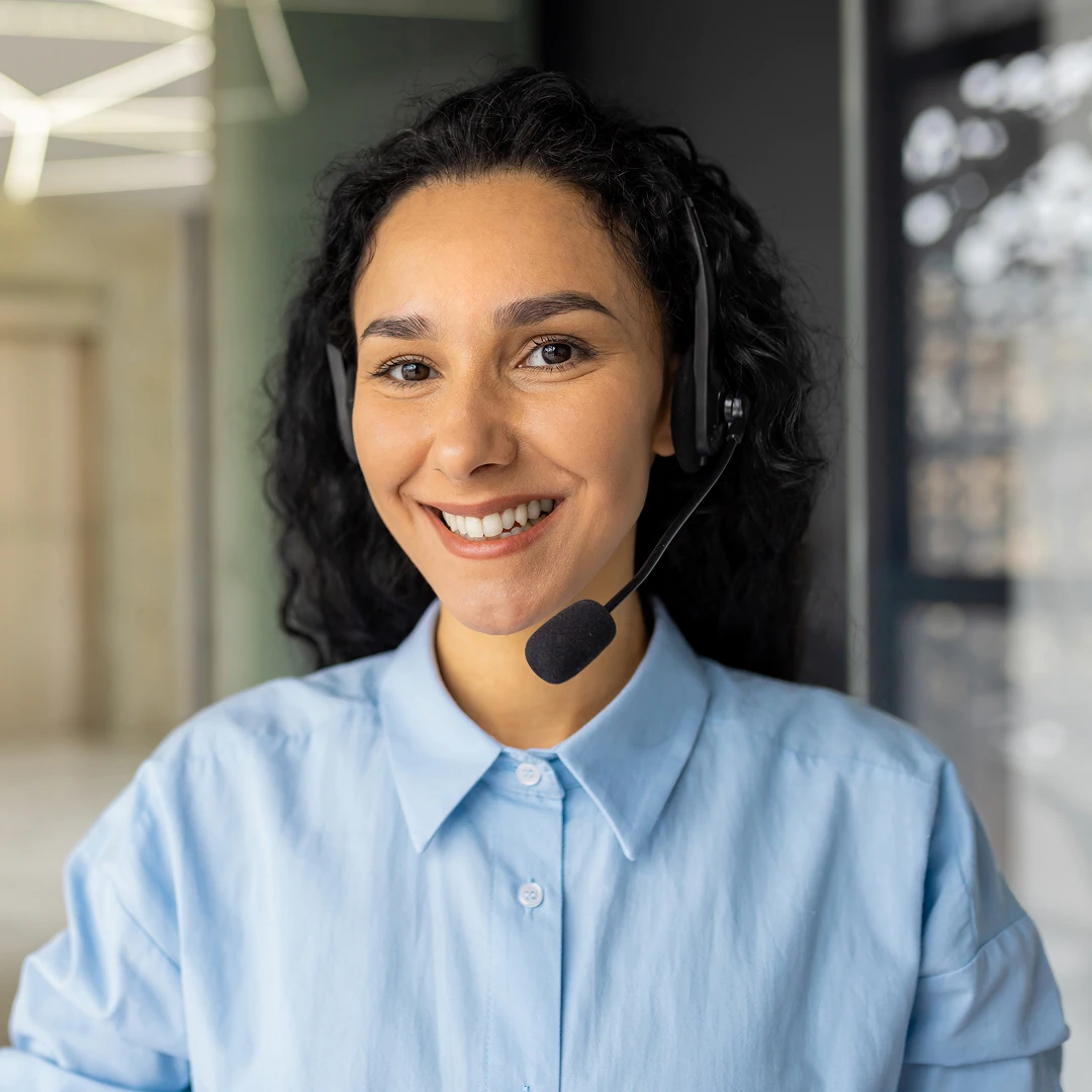 Smiling female customer support representative wearing a headset and a light blue shirt