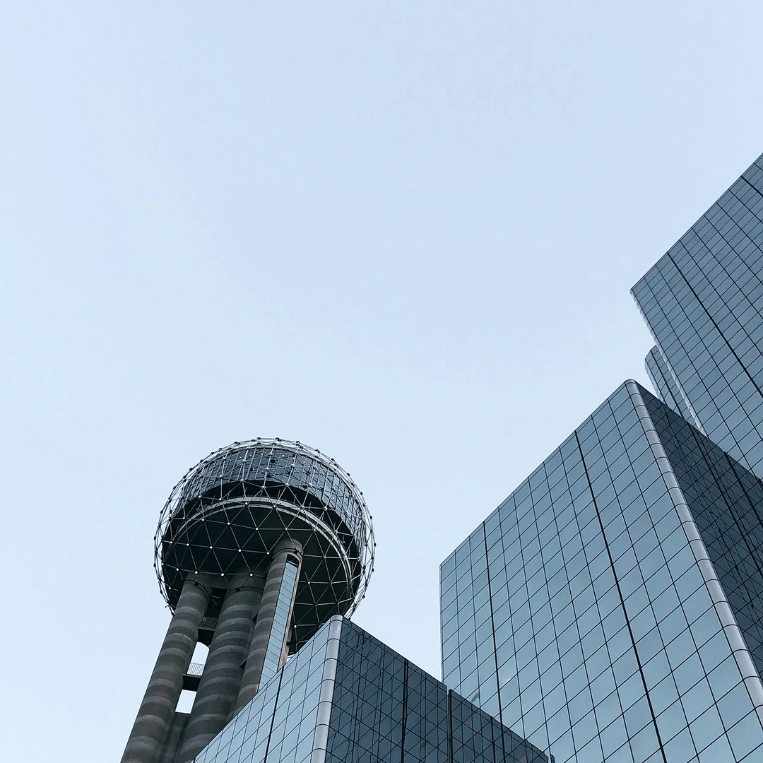 Reunion Tower and modern office buildings against a pale sky in Dallas