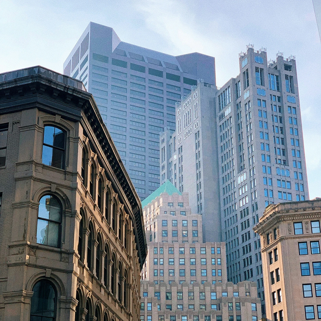 Historic-style building with modern skyscrapers in the background under a cloudy sky