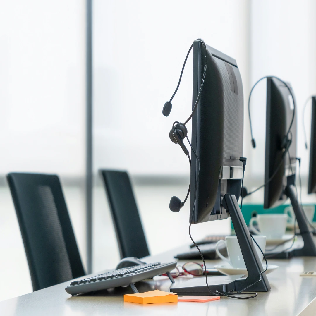 Computer monitors and headsets in an empty ecommerce call center workspace