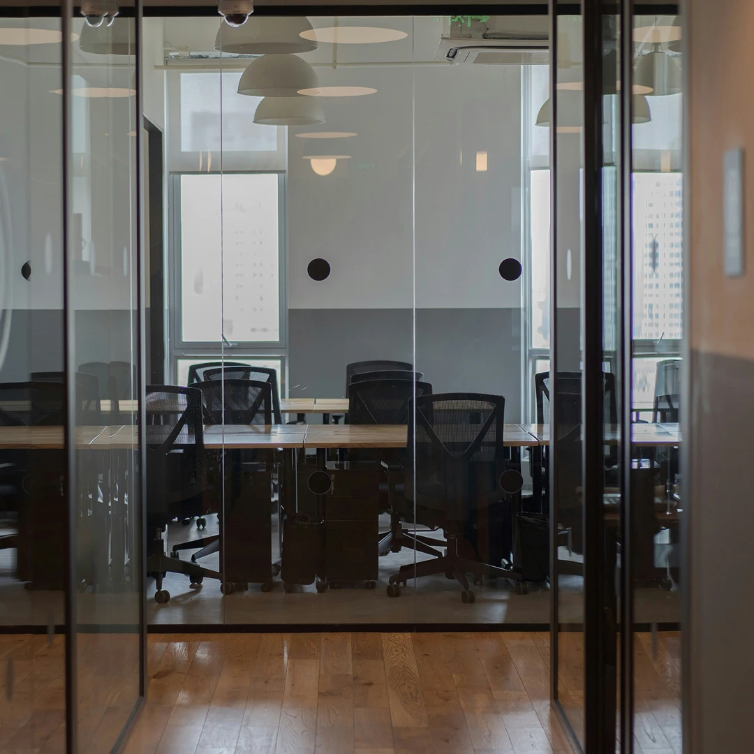 Interior of a contemporary office space with a glass-enclosed meeting room