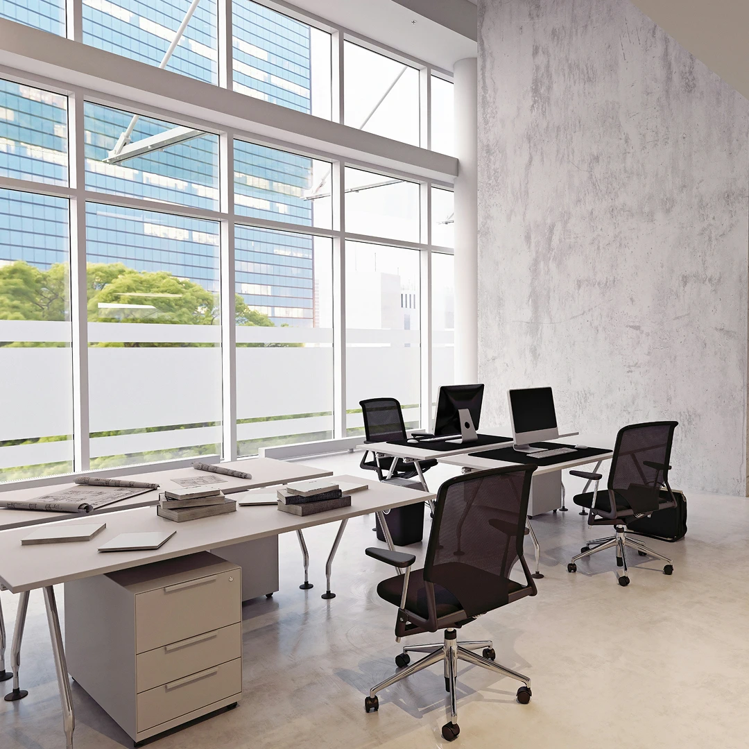 open office space with large windows offering a city view, clean-lined desks, and rolling chairs