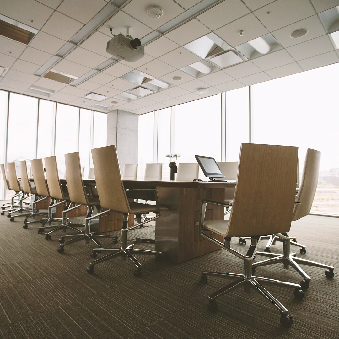Conference room with a long table, comfortable chairs, and large windows letting in natural light
