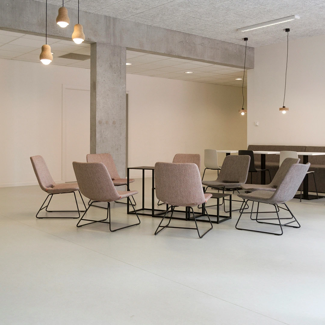 Interior design featuring fabric chairs with black metal frames, small black tables, and modern pendant lighting