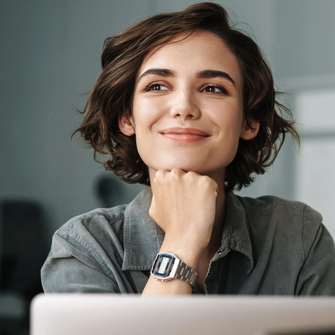 Woman with short hair looking up and smiling with her chin resting on her hand