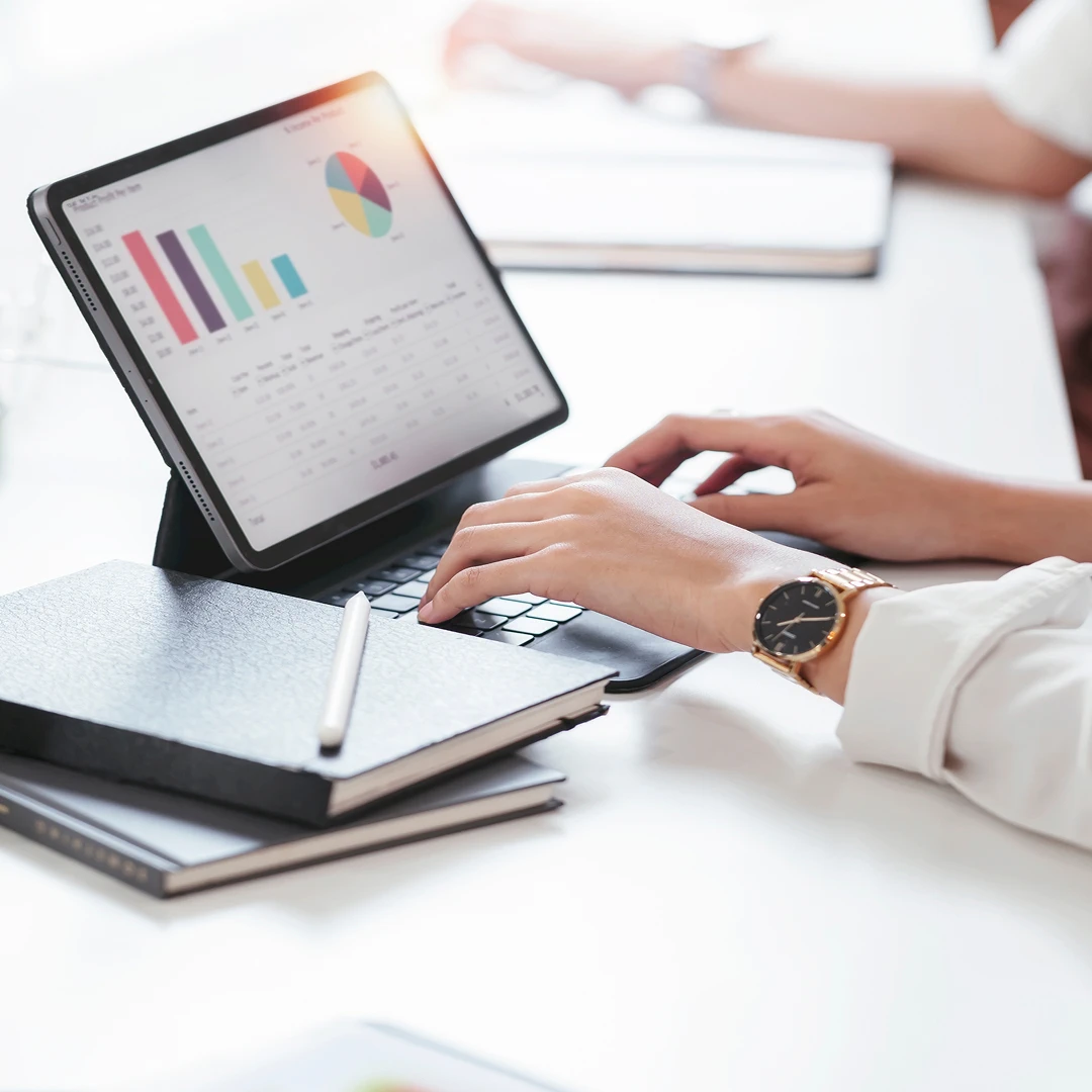Hands typing on a tablet keyboard displaying charts and graphs
