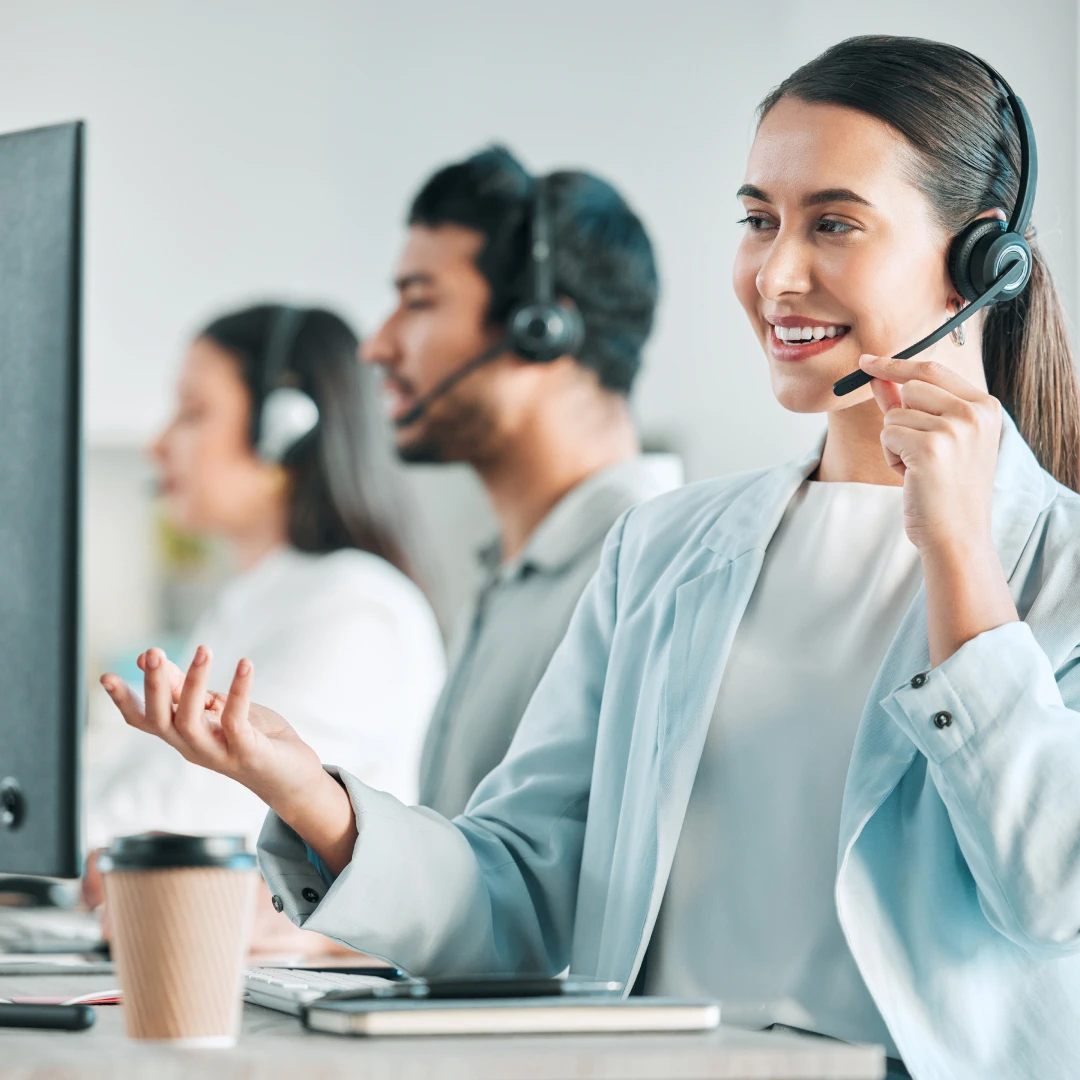 Customer service representatives working at computers, wearing headsets, providing support in a call center in Boston