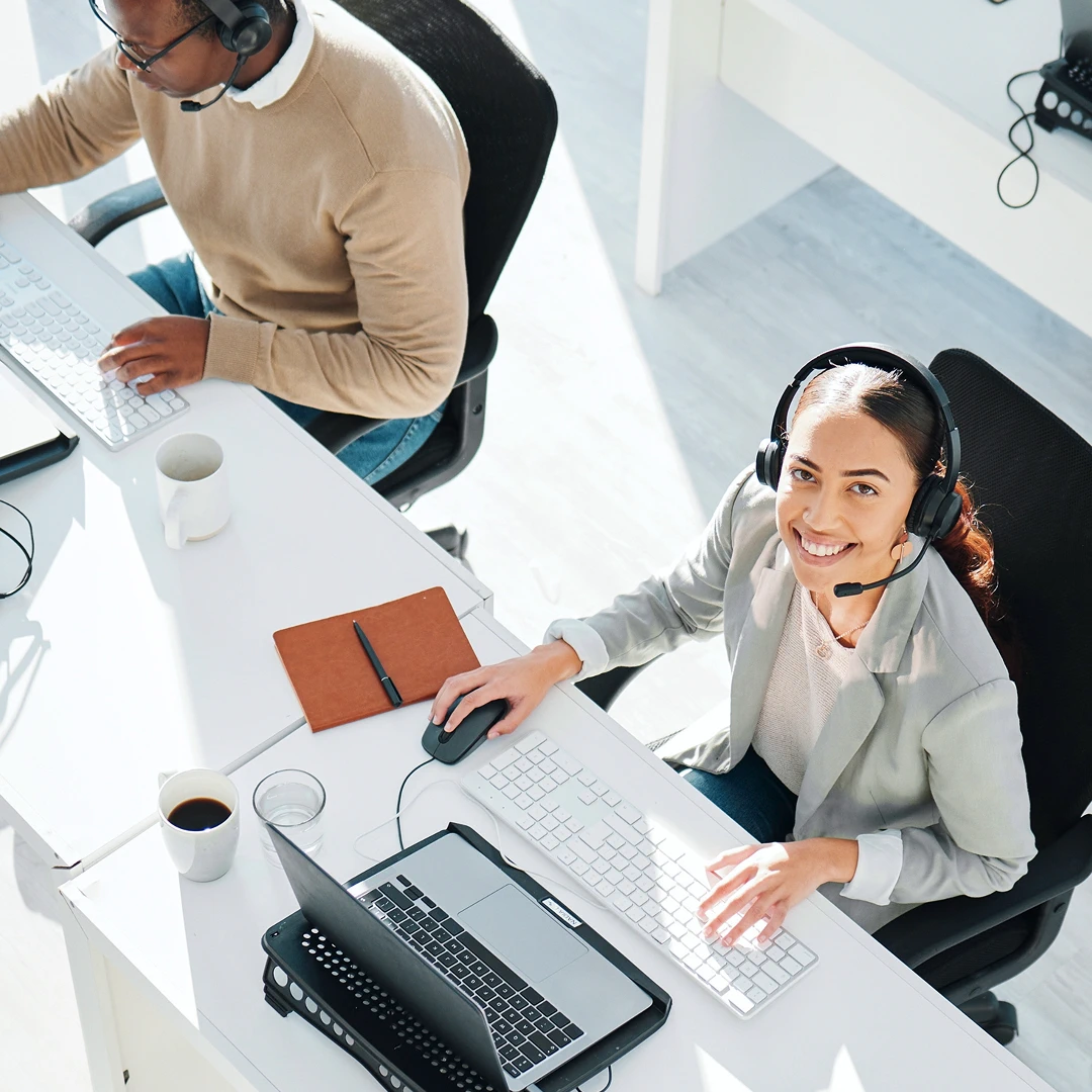 Group of customer service representatives seen from a high angle, working at desks in a brightly lit Hartford call center