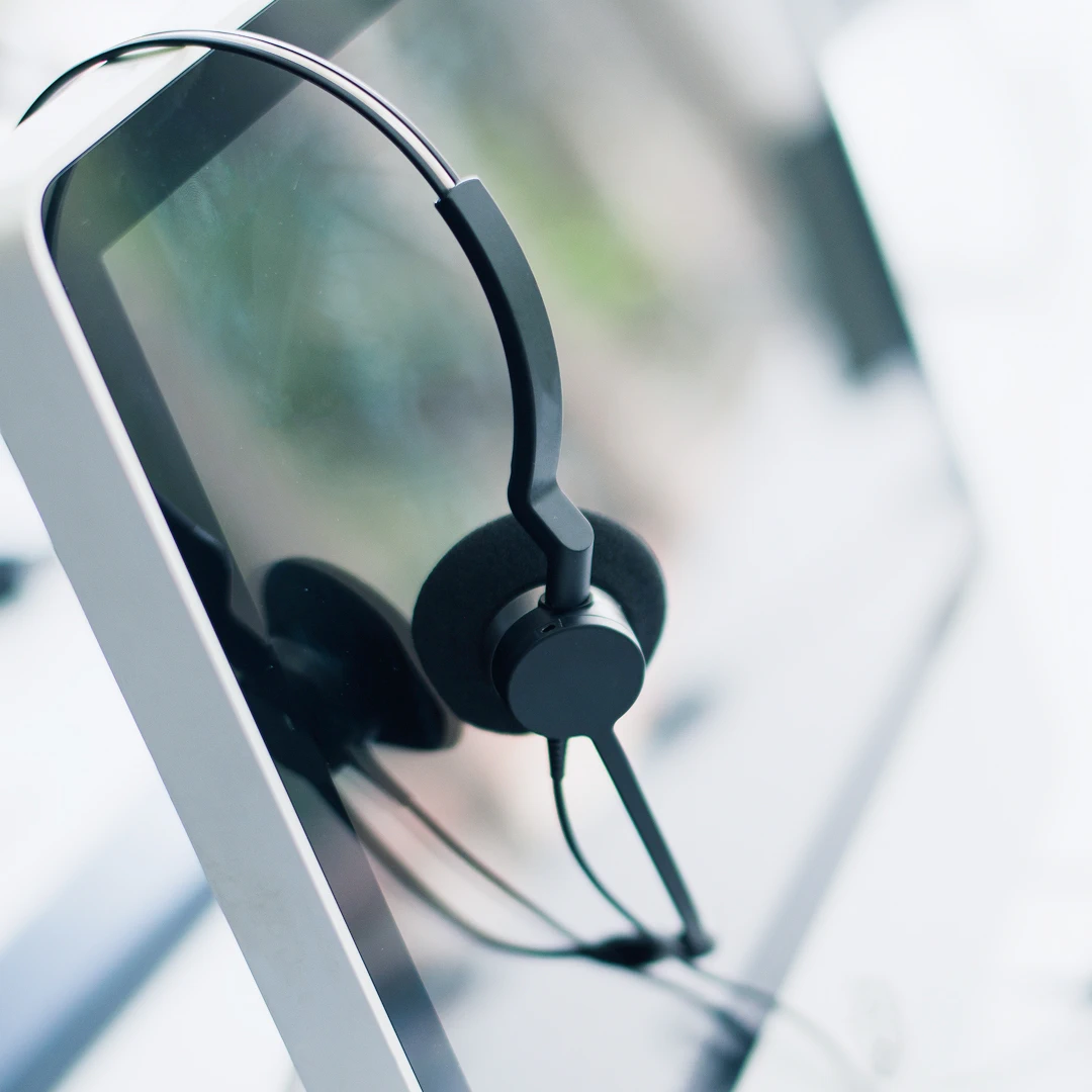 Headphones with a microphone hanging on a computer monitor