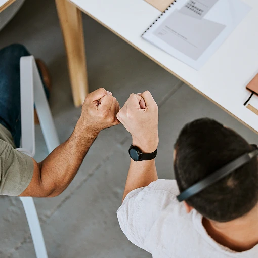 Overhead view of two people bumping fists to celebrate teamwork and agreement
