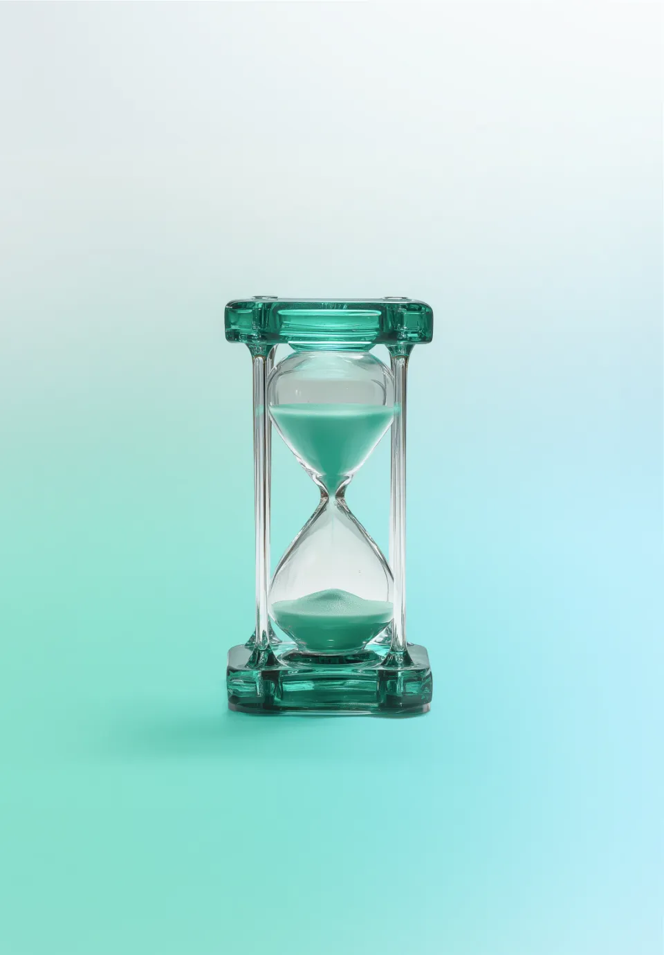 An hourglass with a transparent frame and white sand, on a light blue-green background.