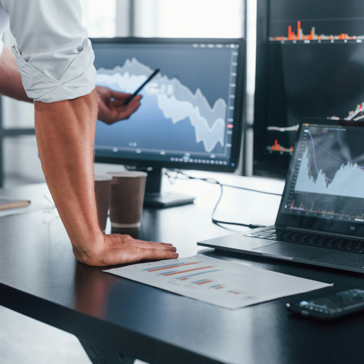 a man standing with a pen in front of a screen with some graph