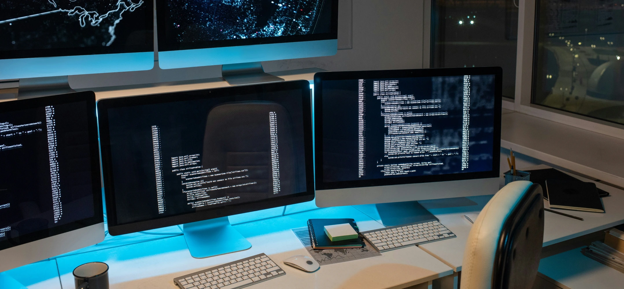 three apple monitors displaying lines of code, no developers around