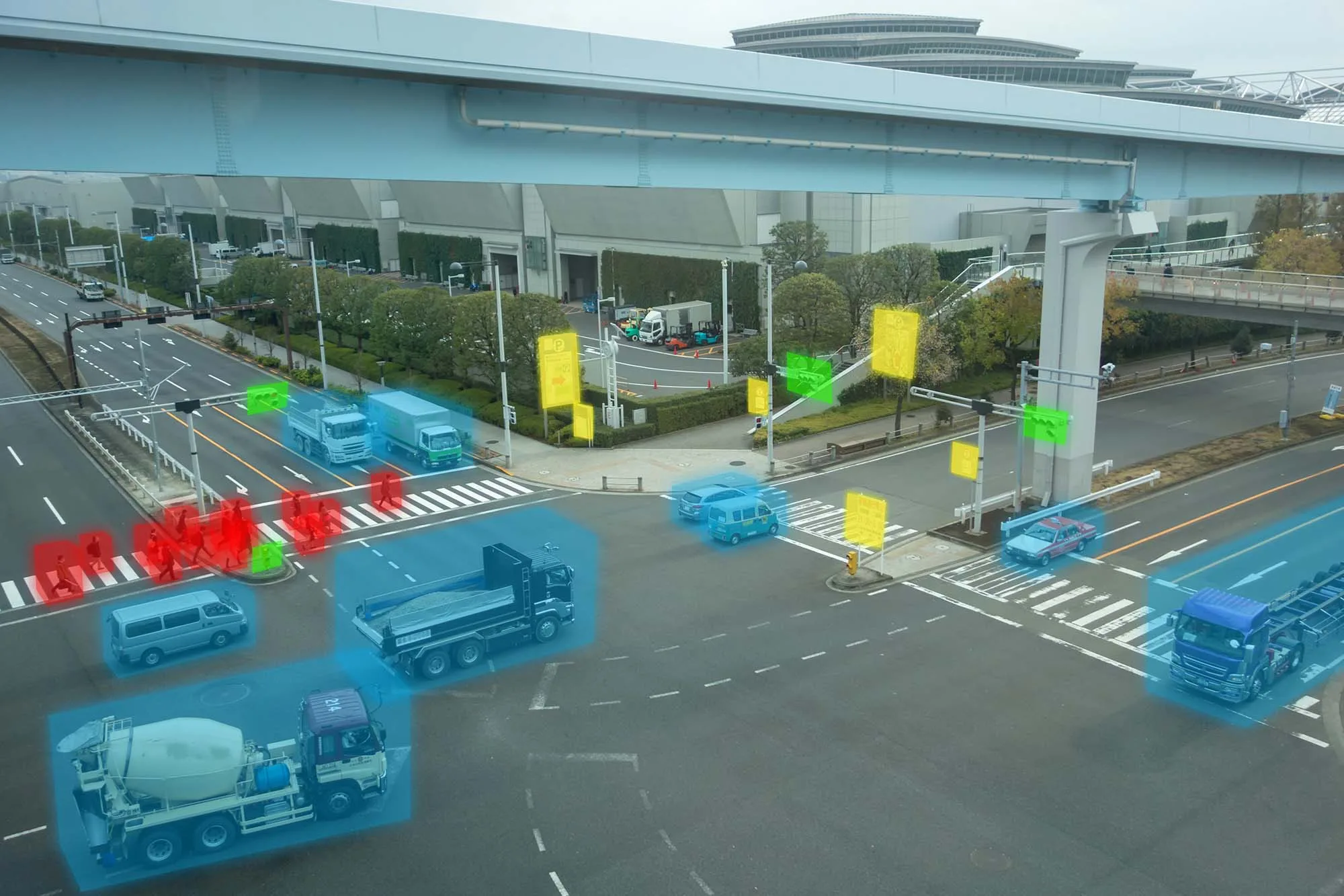 A city intersection with multiple vehicles, including cars and trucks, overlaid with colorful digital detection graphics