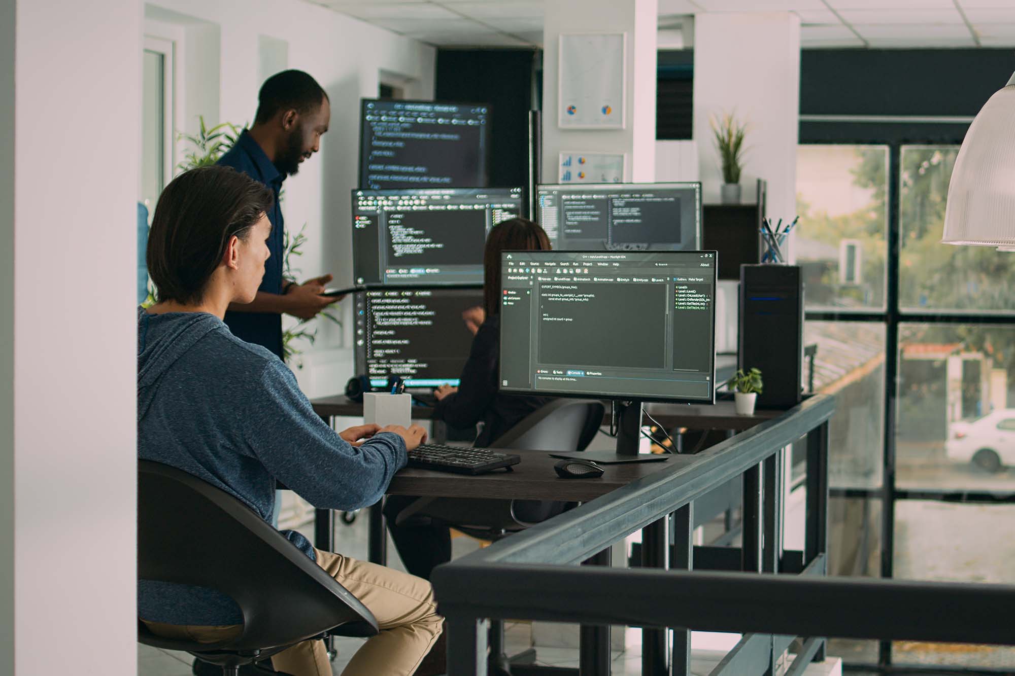 AI developers working on multiple monitors, coding, analyzing data, and refining machine learning models.