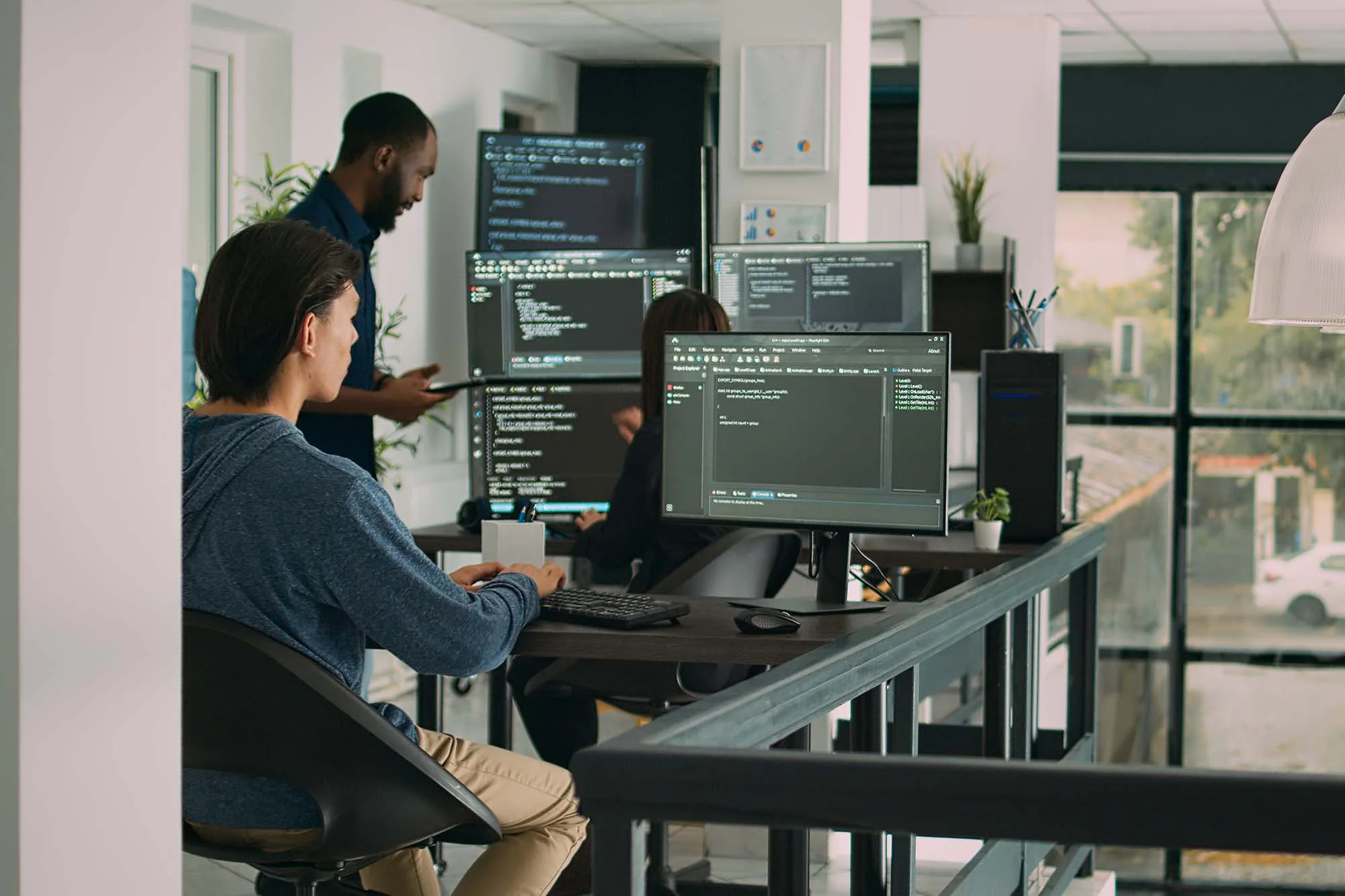 AI developers working on multiple monitors, coding, analyzing data, and refining machine learning models.