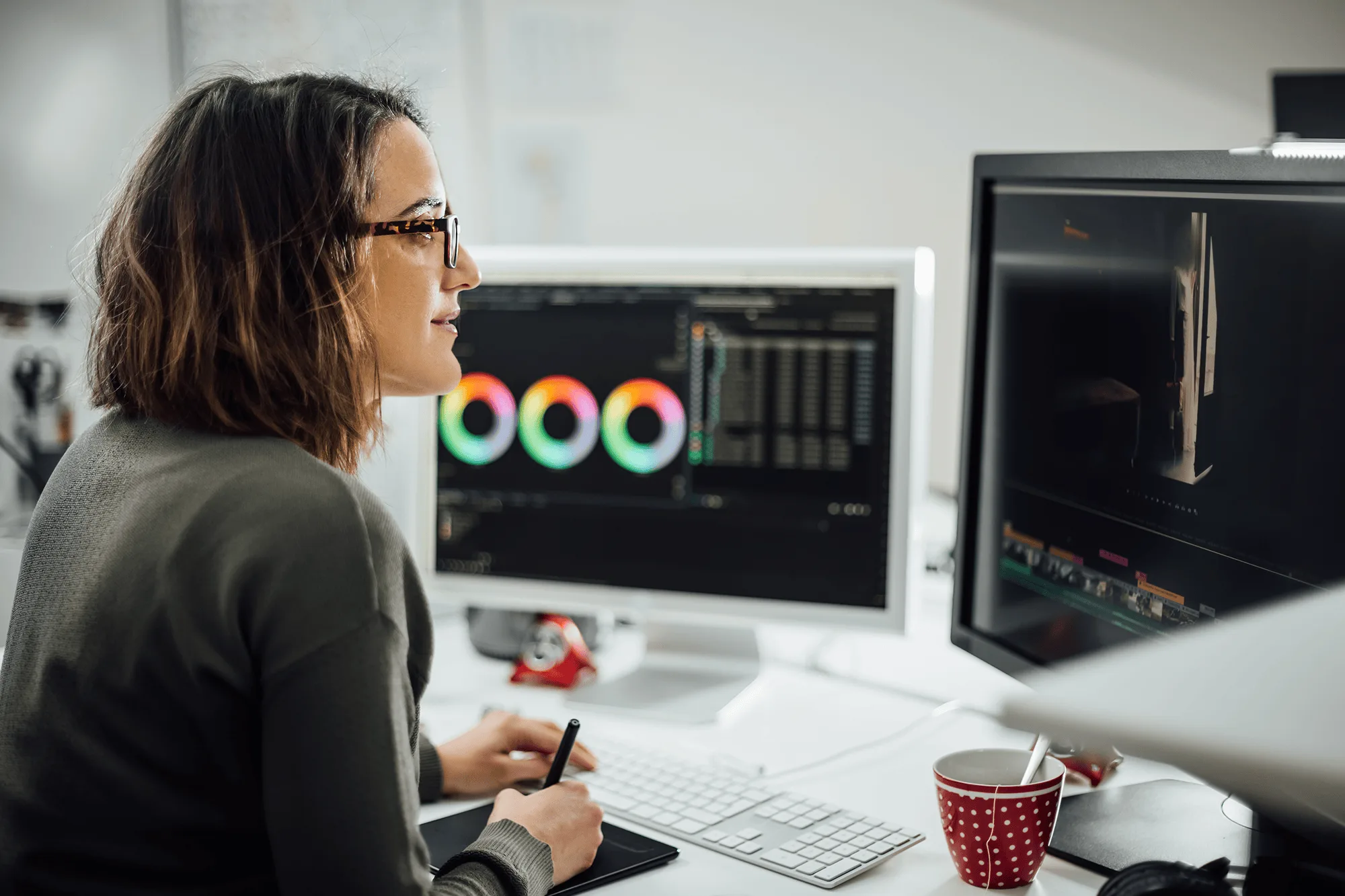 Woman analyzing data visualizations on computer monitors.