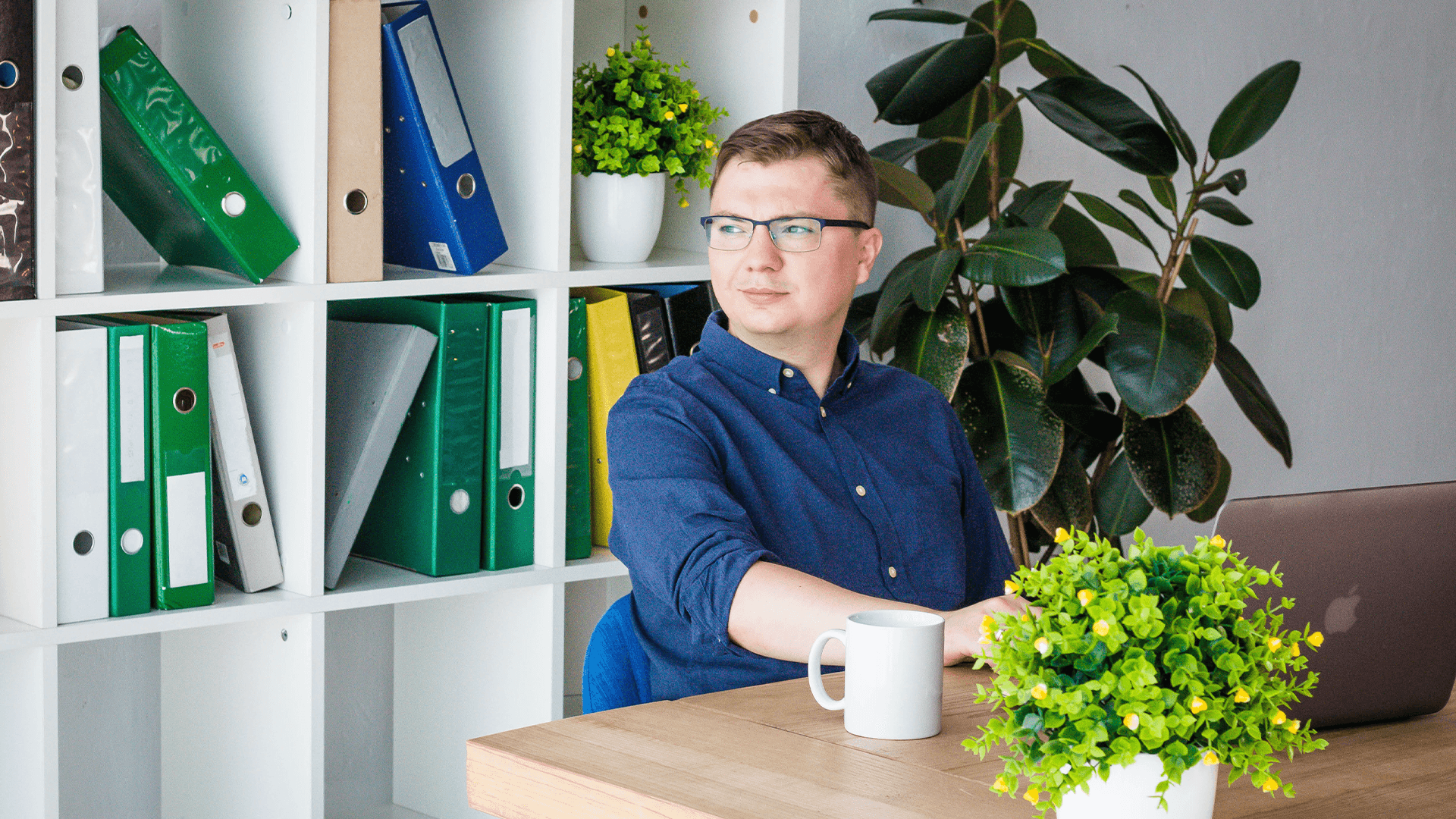 Helpware’s VP of Marketing, is sitting at a desk with a bookshelf full of folders behind him