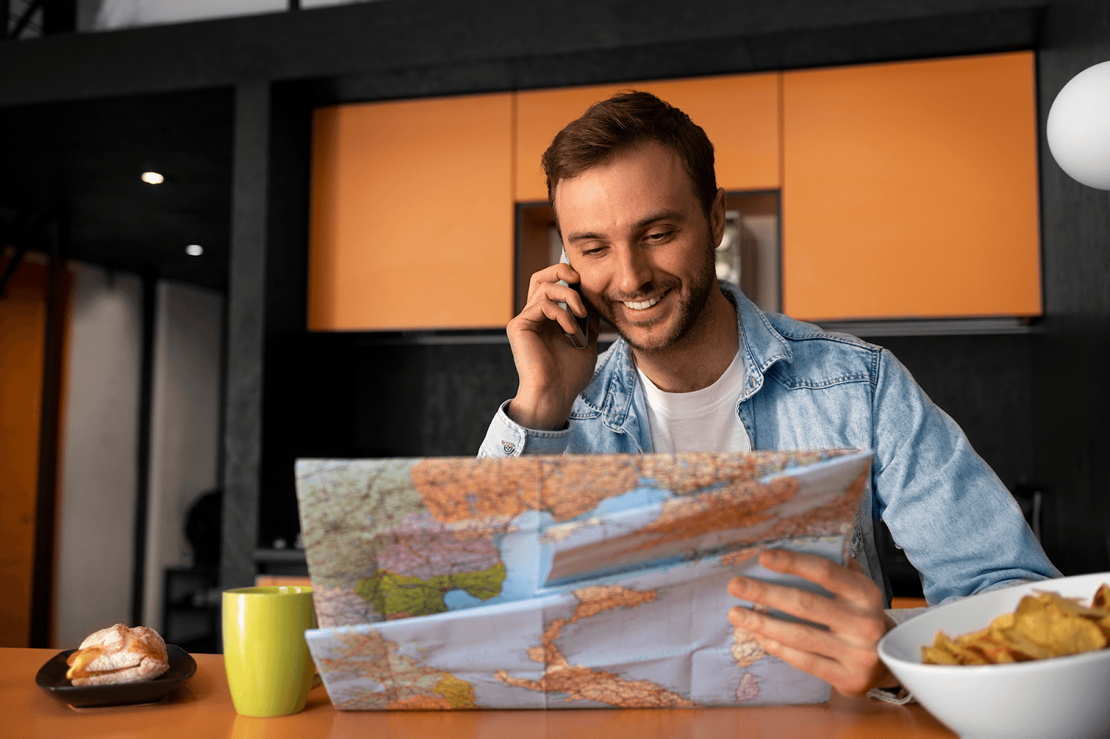 A man smiles as he talks on his cellphone while studying a paper map