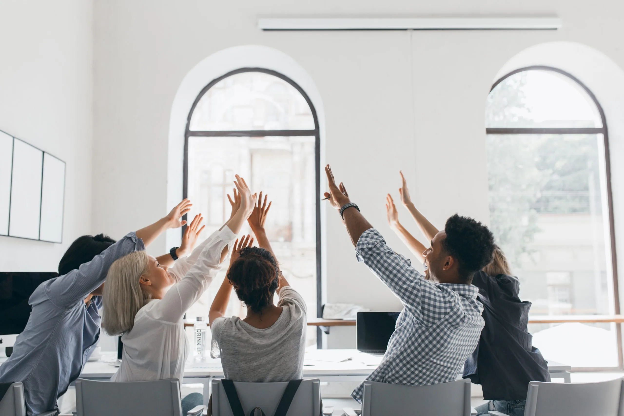 A team celebrates a success with a high-five in a bright office