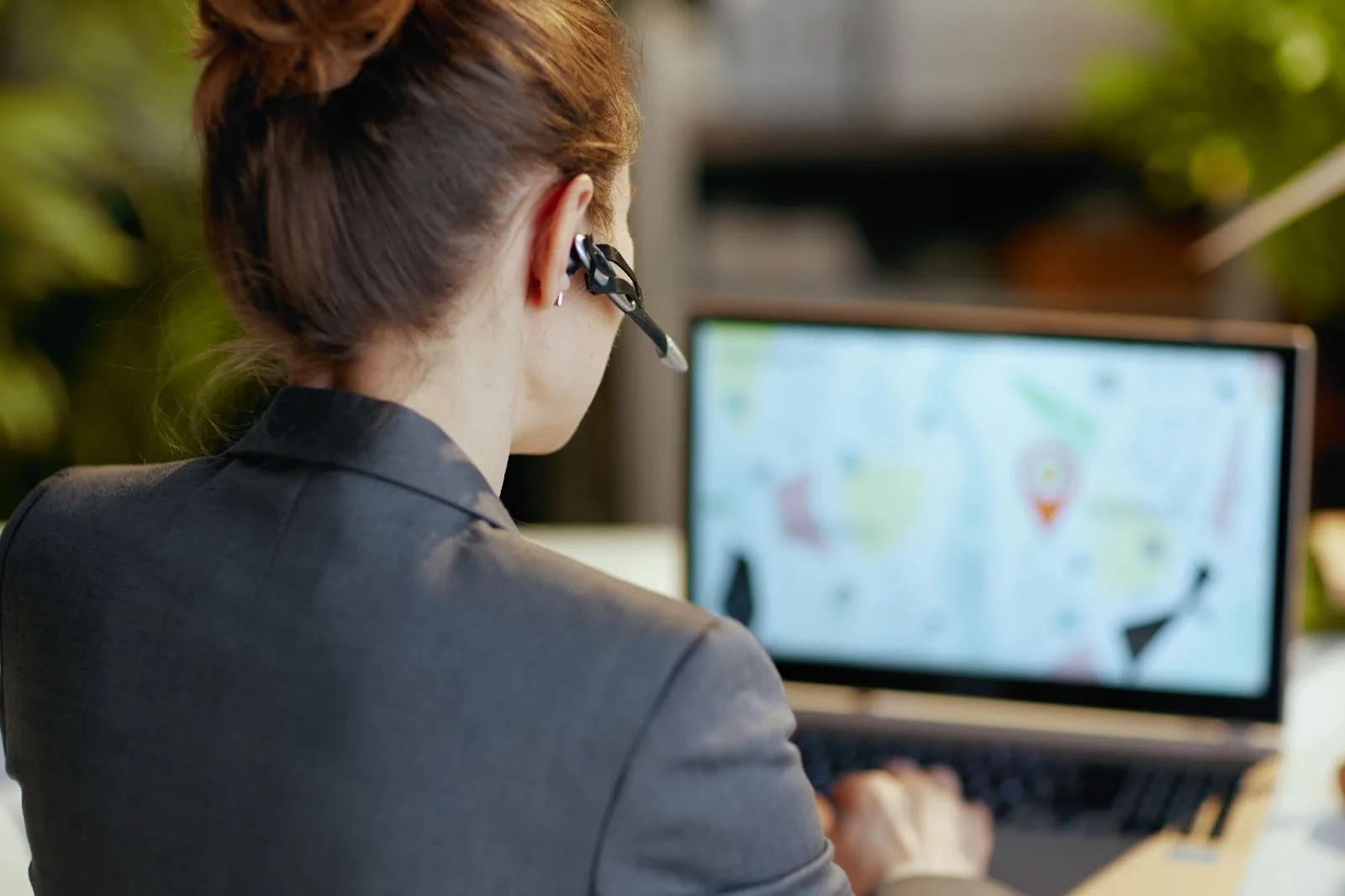 A back view of a woman wearing a business suit and a headset as she provides diligent customer support.
