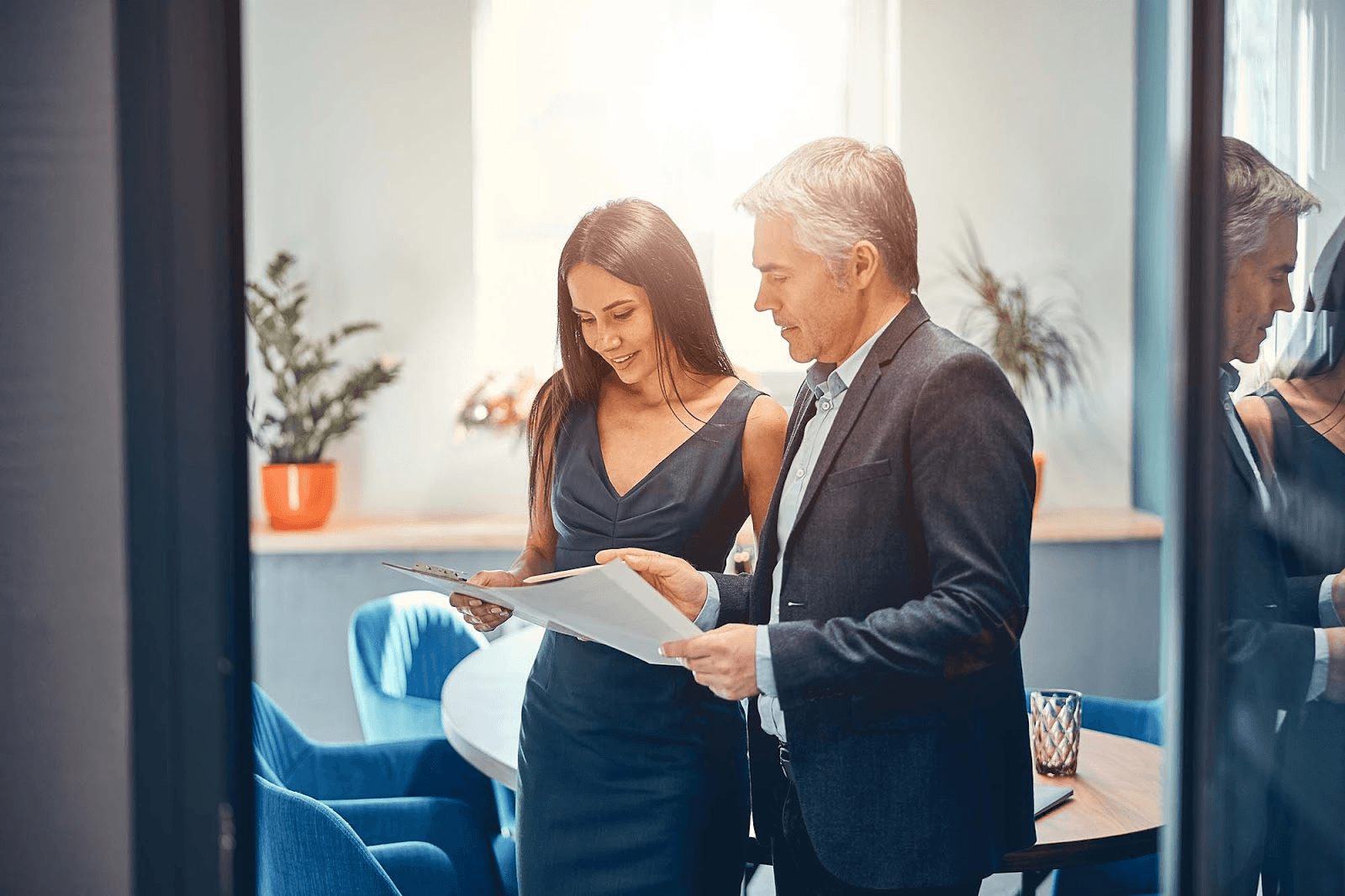 A business meeting with a woman and a man wearing suits, reviewing documents.
