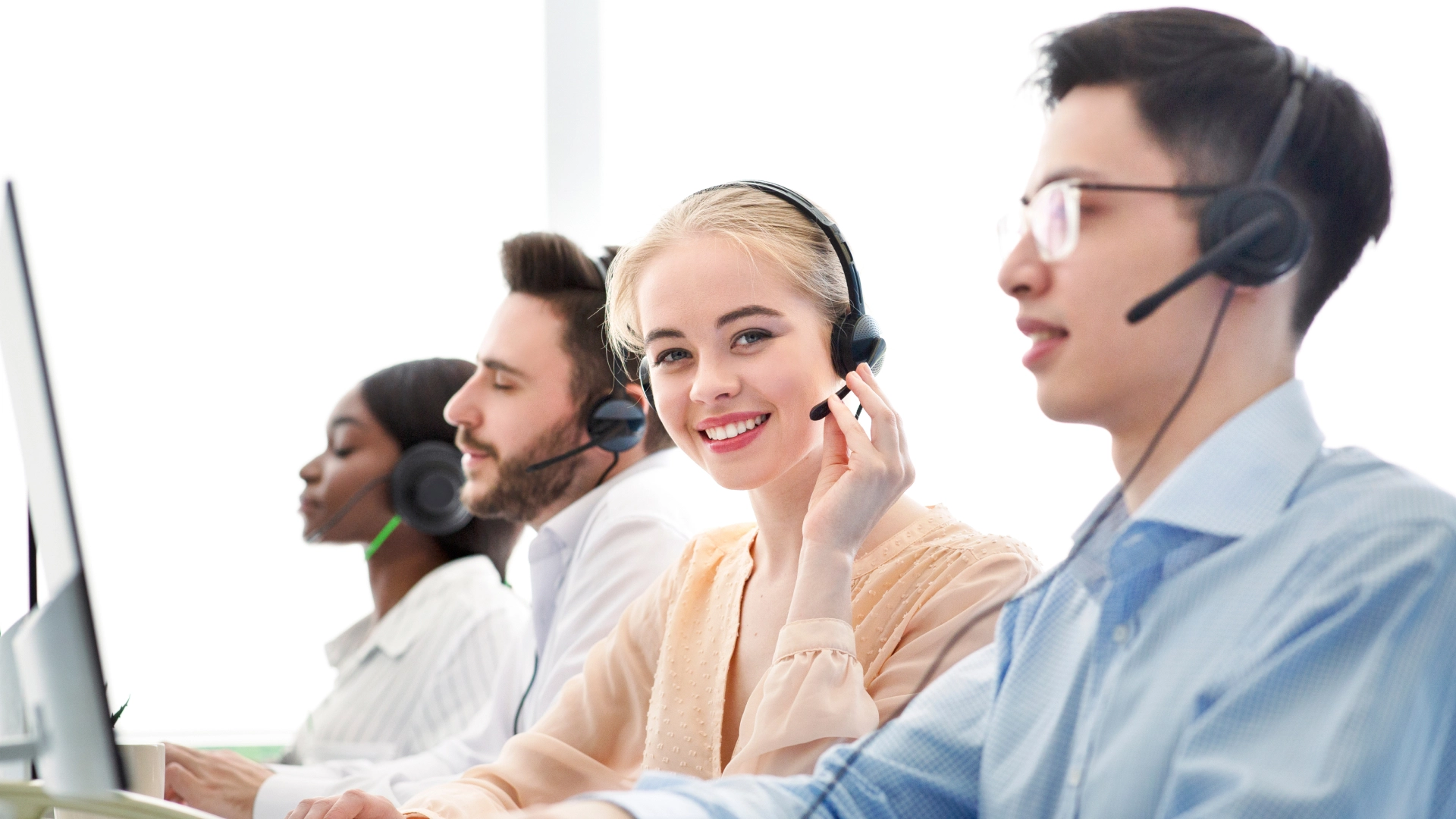 Customer service representatives wearing headsets, working in a bright and professional call center environment.
