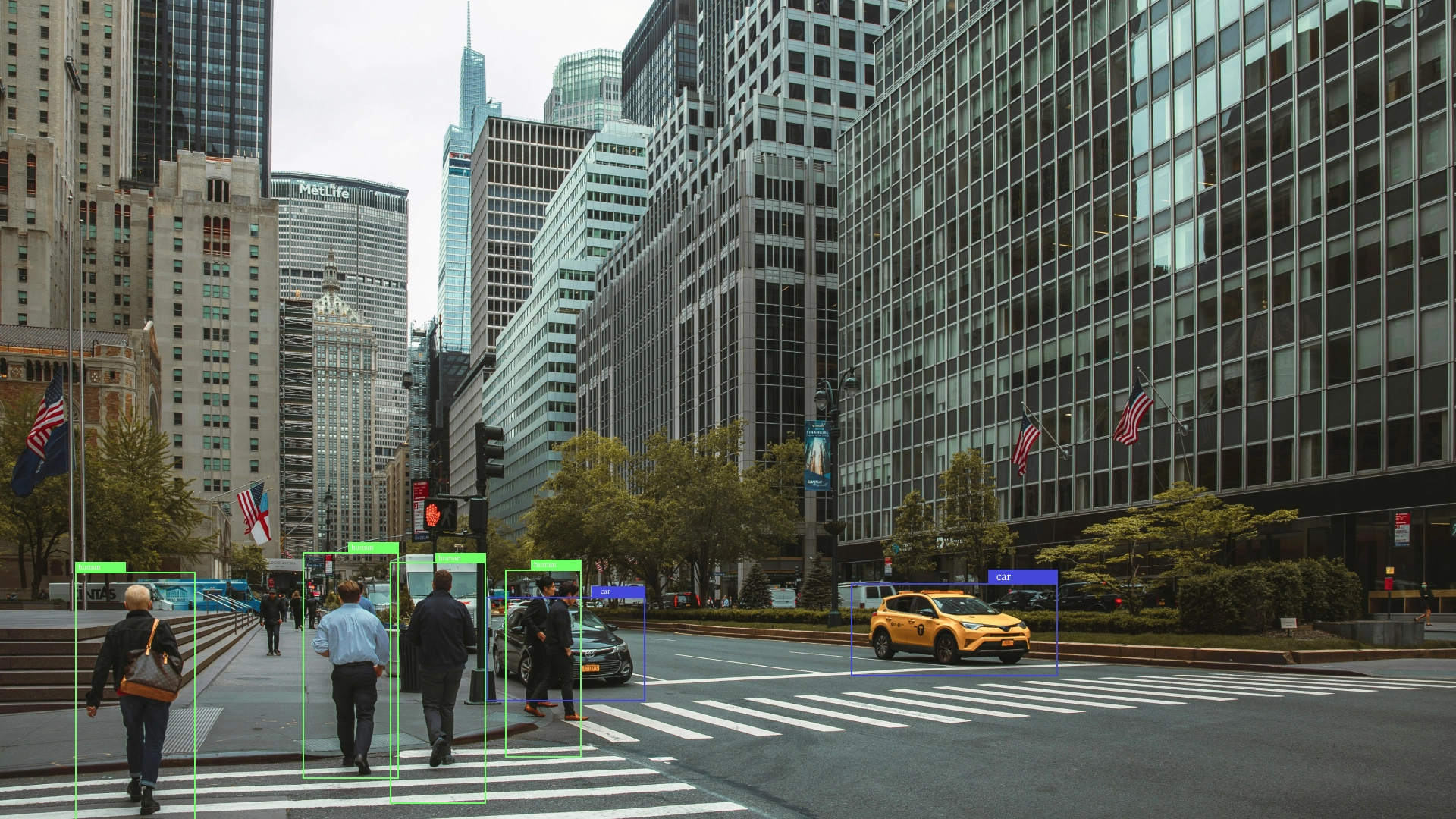 Urban street scene in New York City, featuring buildings and cars, with object detection boxes highlighting people and vehicles.