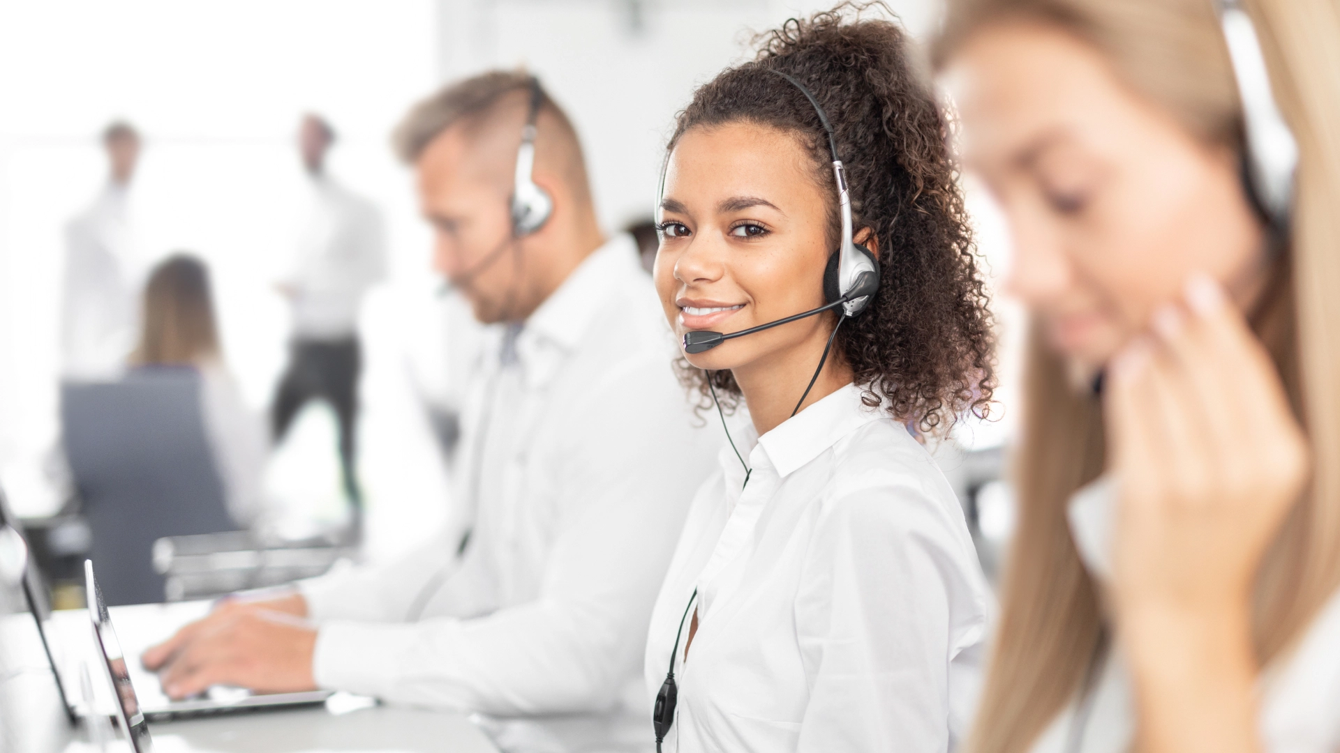 Woman with curly hair wearing a headset, representing friendly and professional customer service.