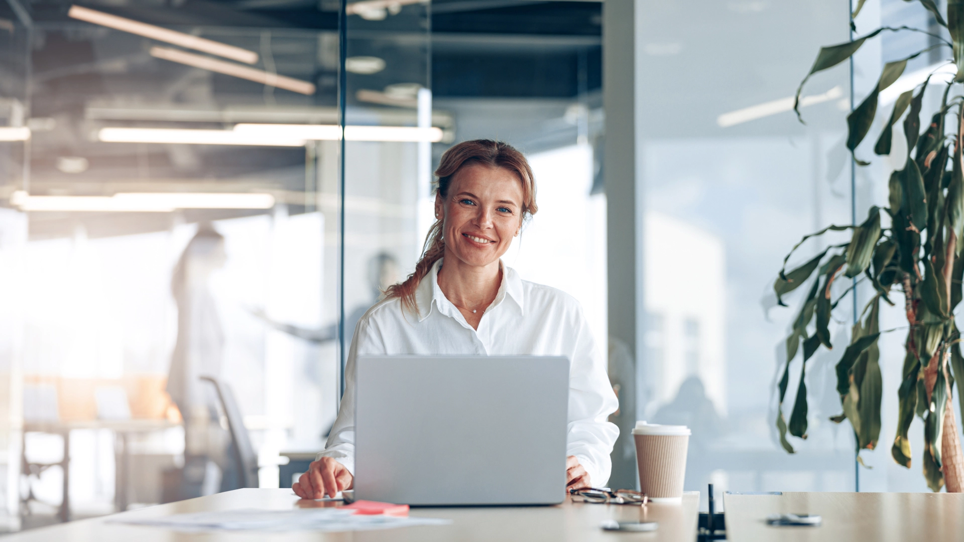Professional woman working on a laptop in a bright, modern office space.