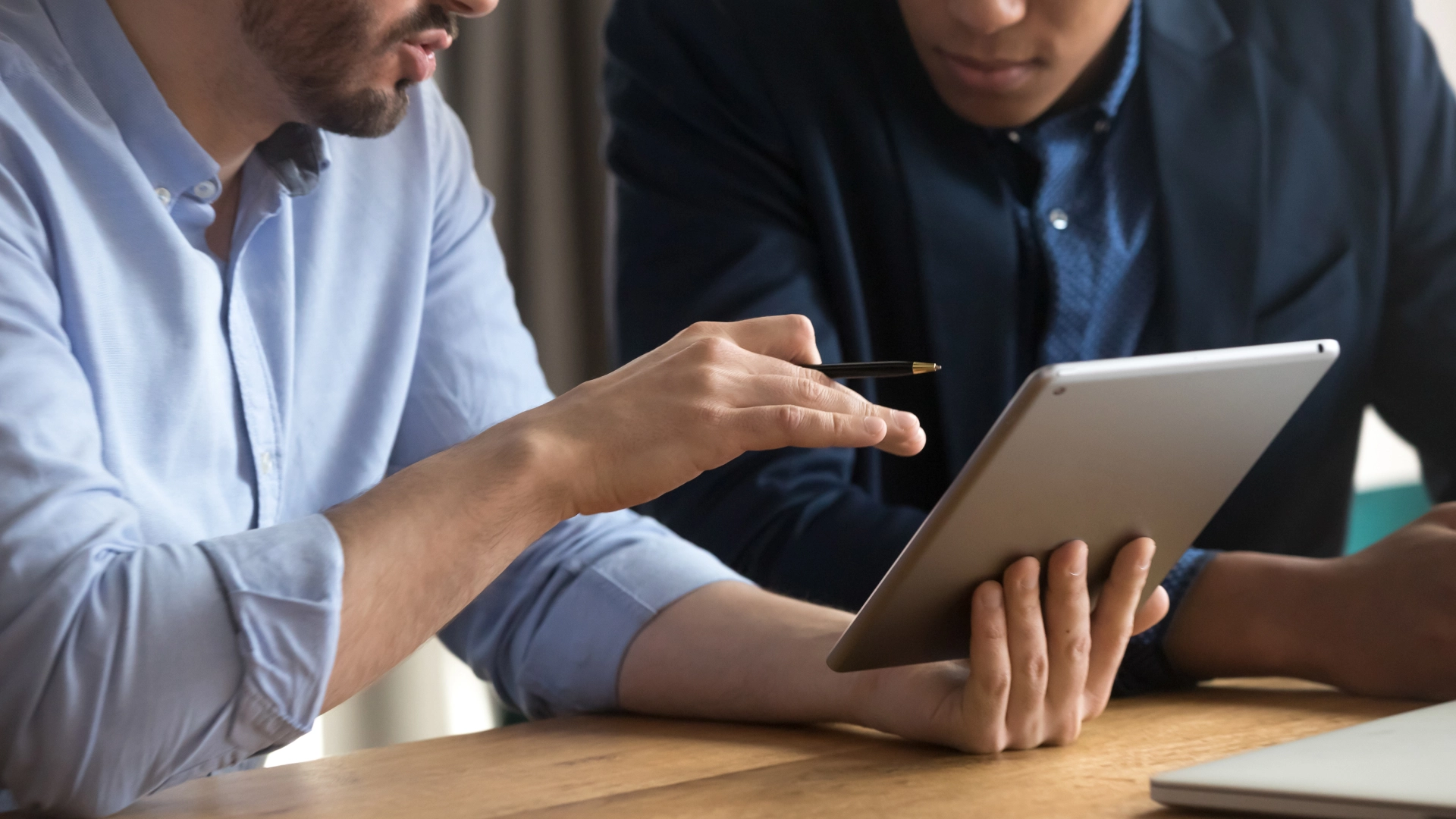 Two business professionals reviewing data on a tablet device.